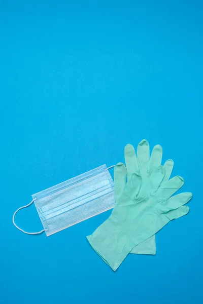 Disposable blue medical face mask and rubber latex gloves on blue background — Stock Photo, Image