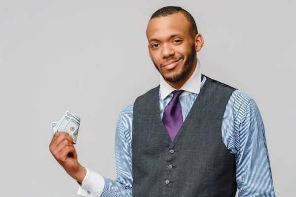 Retrato del joven afroamericano emocionado sosteniendo dinero en efectivo sobre fondo gris claro —  Fotos de Stock