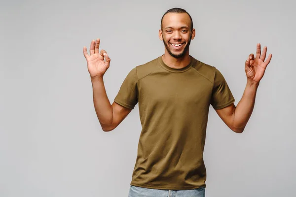 Gioioso amichevole afro-americano giovane in t-shirt verde showin og segno gesto su sfondo grigio chiaro con spazio copia — Foto Stock