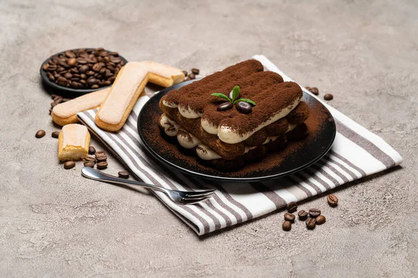 Dolce tiramisù classico e biscotti savoiardi su piatto di ceramica su fondo di cemento — Foto Stock