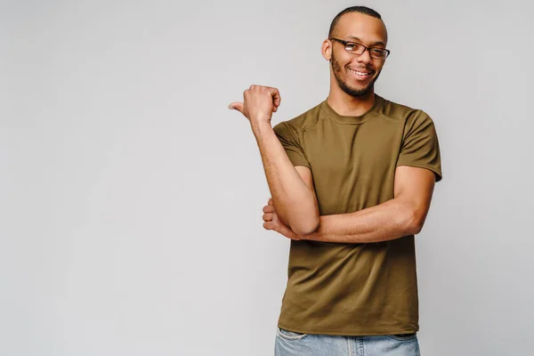 Joyful amigável jovem afro-americano em t-shirt verde apontando por dedo no espaço de cópia — Fotografia de Stock