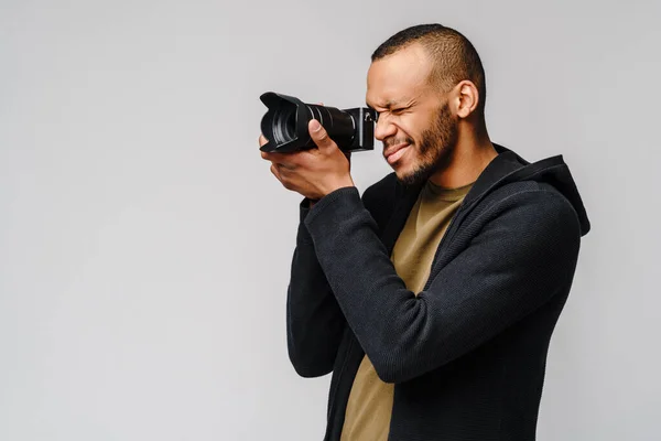 Handsome african american guy holding digital camera over light gray background — Stock Photo, Image