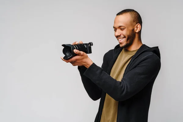 Bello afro americano ragazzo tenendo digitale fotocamera su luce grigio sfondo — Foto Stock