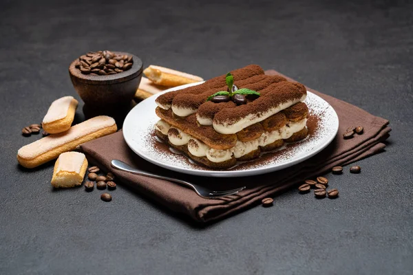 Klasik tiramisu tatlısı ve çimento arka planda seramik tabakta savoiardi kurabiyeleri. — Stok fotoğraf