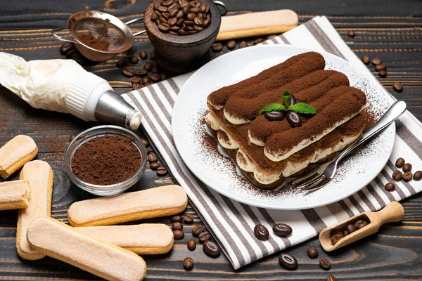 Klasyczny deser tiramisu i savoiardi ciasteczka na płycie ceramicznej na drewnianym tle — Zdjęcie stockowe