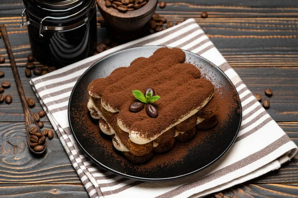 Классический десерт тирамису и кофемолка на керамической пластине на деревянном фоне — стоковое фото