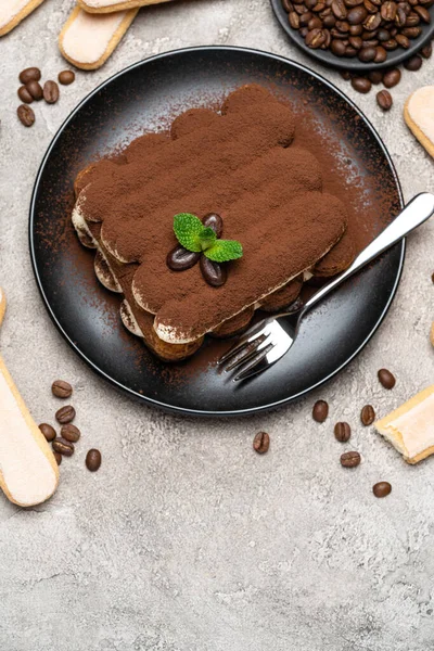 Klassisches Tiramisu-Dessert auf Keramikteller und savoiardi-Kekse auf Betongrund — Stockfoto