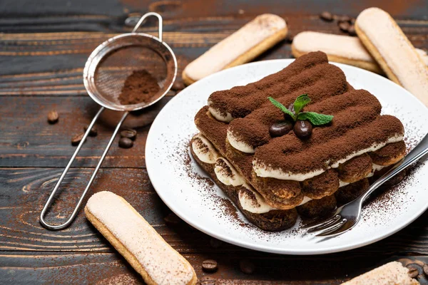 Seramik tabakta klasik tiramisu tatlısı ve ahşap zeminde savoiardi kurabiyesi. — Stok fotoğraf