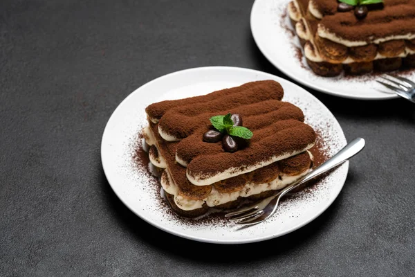 Deux portions de dessert tiramisu classique sur plaque de céramique sur fond de béton — Photo