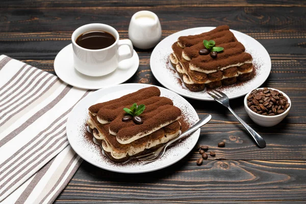 Dwie porcje klasycznego deseru tiramisu, filiżanka kawy i mleka lub śmietany na drewnianym tle — Zdjęcie stockowe