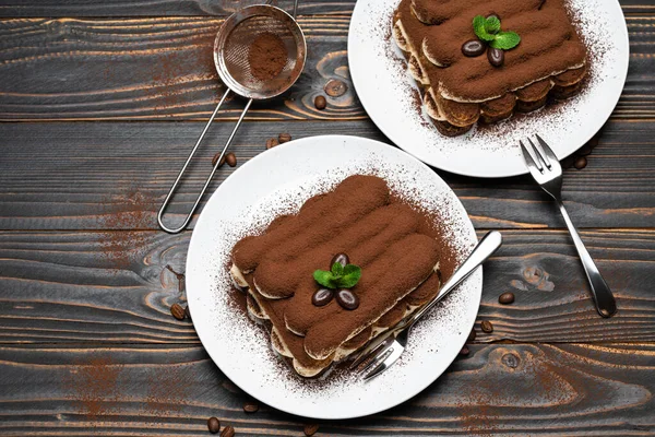 Zwei Portionen klassisches Tiramisu-Dessert auf Keramikteller auf Holzgrund — Stockfoto