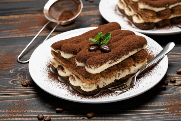 Zwei Portionen klassisches Tiramisu-Dessert auf Keramikteller auf Holzgrund — Stockfoto