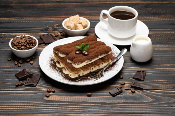 Часть классического десерта тирамису, чашка кофе и молока или сливки на деревянном фоне — стоковое фото