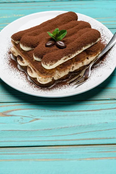 Porção de sobremesa tiramisu clássico na placa de cerâmica no fundo de madeira azul colorido — Fotografia de Stock