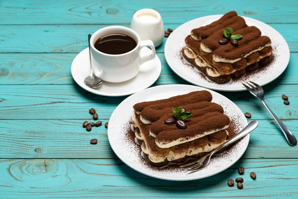 Zwei Portionen klassisches Tiramisu-Dessert, Tasse Kaffee und Milch oder Sahne auf buntem, blauem Holzhintergrund — Stockfoto