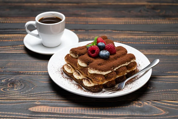 Porsi makanan penutup klasik tiramisu dengan raspberry, blueberry dan secangkir kopi espresso terisolasi dengan latar belakang kayu — Stok Foto