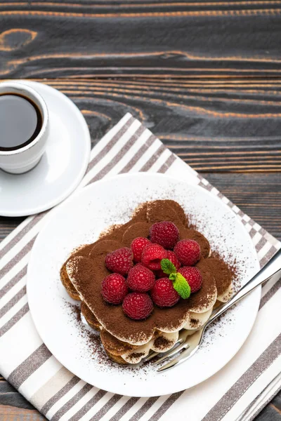 Portie Classic tiramisu dessert met frambozen en kopje espresso koffie geïsoleerd op houten achtergrond — Stockfoto