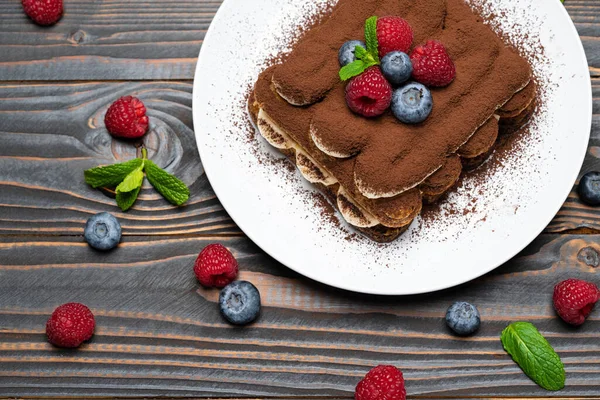 Portion de dessert classique tiramisu avec framboises et bleuets sur fond de bois — Photo