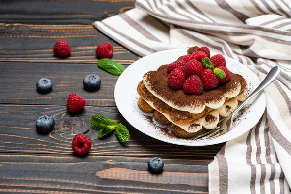 Portion de dessert classique tiramisu avec framboises et bleuets sur fond de bois — Photo