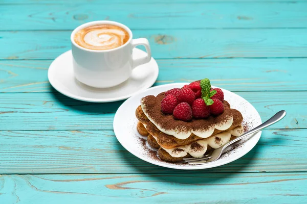 Portion klassisches Tiramisu-Dessert mit Himbeeren und Tasse Espresso auf blauem Holzgrund — Stockfoto