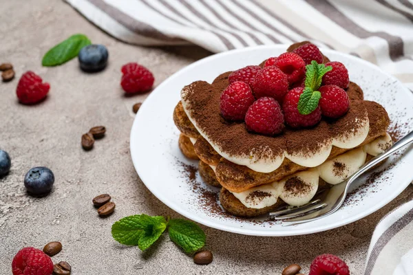 Porción de postre tiramisú clásico con frambuesas y arándanos sobre fondo de hormigón gris — Foto de Stock