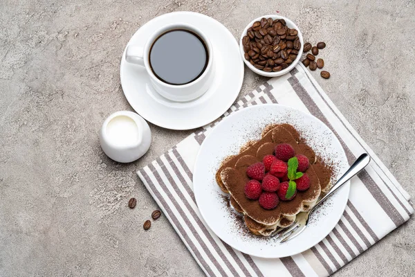 Часть классического десерта тирамису с малиной и чашкой кофе и сливок или молока на сером бетонном фоне — стоковое фото