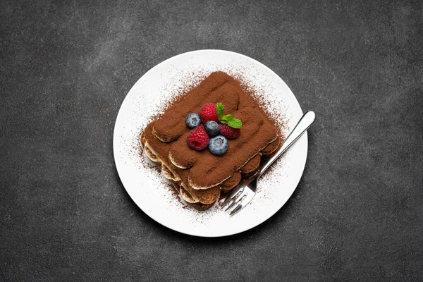 Часть классического десерта тирамису с малиной и черникой на темно-бетонном фоне — стоковое фото