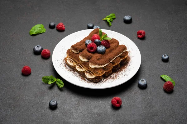 Portion de dessert classique tiramisu aux framboises et aux bleuets sur fond de béton foncé — Photo