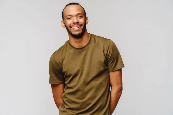 Gioioso amichevole africano-americano giovane in t-shirt verde su sfondo grigio chiaro con spazio copia — Foto Stock