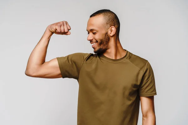 Ritratto ravvicinato di un felice uomo afro-americano che indossa t-shirt flessione bicipite braccio muscolare — Foto Stock