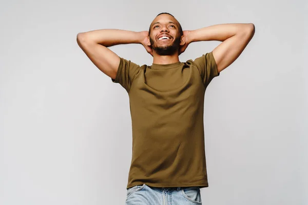 Vreugdevolle vriendelijke Afrikaans-Amerikaanse jongeman in groen t-shirt over lichtgrijze achtergrond met kopieerruimte — Stockfoto