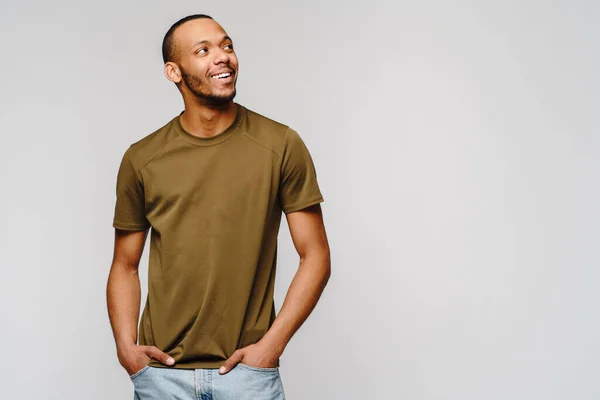 Vreugdevolle vriendelijke Afrikaans-Amerikaanse jongeman in groen t-shirt over lichtgrijze achtergrond met kopieerruimte — Stockfoto