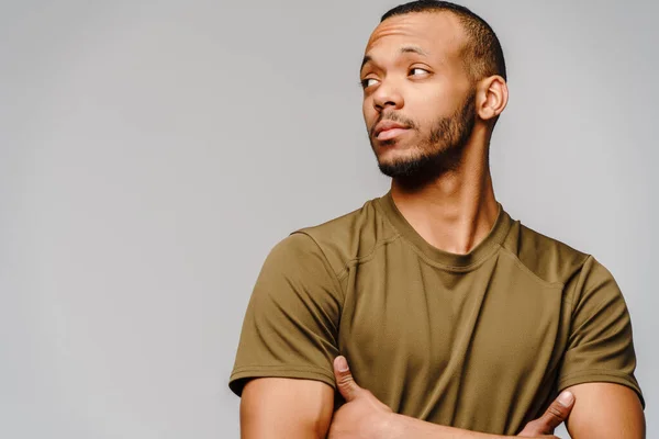 Vreugdevolle vriendelijke Afrikaans-Amerikaanse jongeman in groen t-shirt over lichtgrijze achtergrond met kopieerruimte — Stockfoto