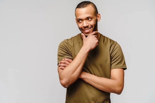 Vreugdevolle vriendelijke Afrikaans-Amerikaanse jongeman in groen t-shirt over lichtgrijze achtergrond met kopieerruimte — Stockfoto