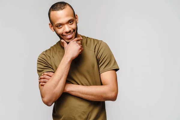Vreugdevolle vriendelijke Afrikaans-Amerikaanse jongeman in groen t-shirt over lichtgrijze achtergrond met kopieerruimte — Stockfoto