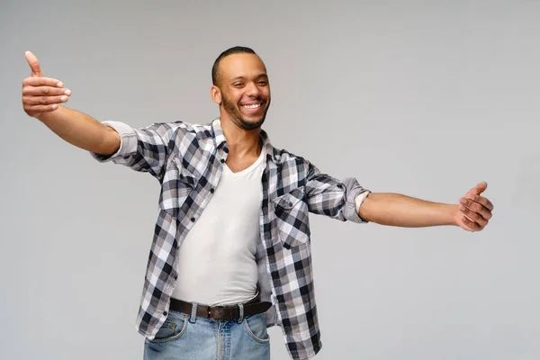 Amigável homem afro-americano vestindo camiseta com sorriso de dente mostrando abraços gesto sobre fundo cinza — Fotografia de Stock
