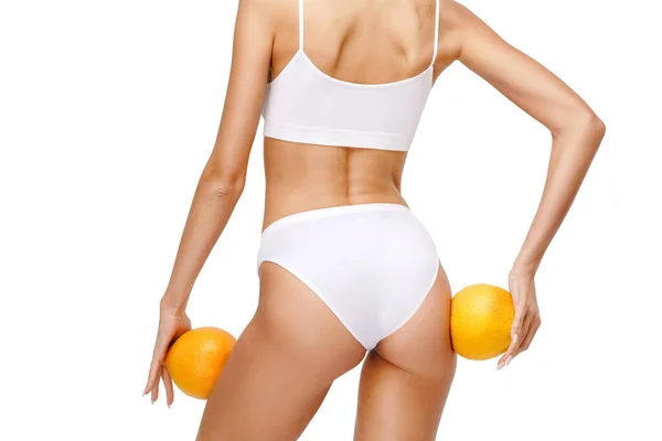 Studio skott av attraktiv ung kvinna med vacker kropp håller orange isolerad på vit — Stockfoto