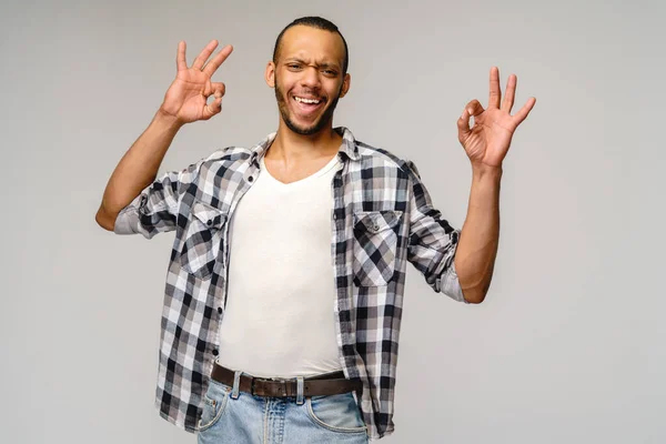 Jovem afro-americano vestindo camisa casual e mostrando ok sinal sobre fundo cinza claro — Fotografia de Stock