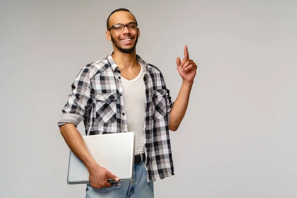 Genç Afrikalı Amerikalı bir adam dizüstü bilgisayarını tutuyor ve boş fotokopi alanına bakıyor. — Stok fotoğraf