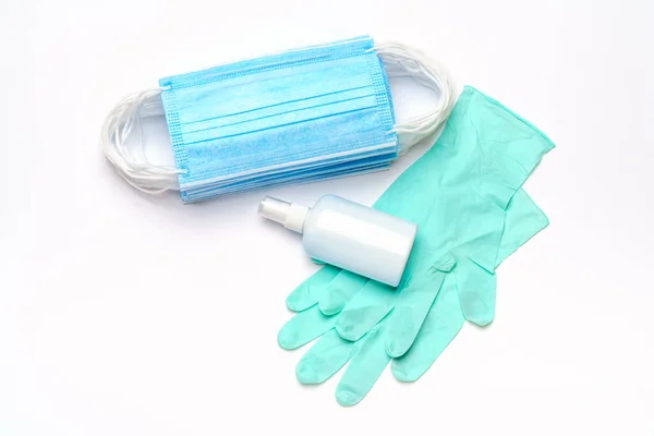 Maschera medica blu monouso, guanti in lattice di gomma e disinfettante per le mani in alcool antisettico su sfondo grigio chiaro — Foto Stock