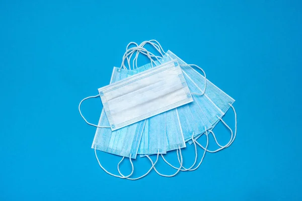Stapel wegwerpbare blauwe medische gezichtsmaskers op blauwe achtergrond — Stockfoto