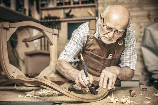 Elderly Carpenter Uses Brush Unfinished Chair — Stock Photo, Image