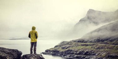 faroe Adaları'nda sarı yağmurluk ile gezgin