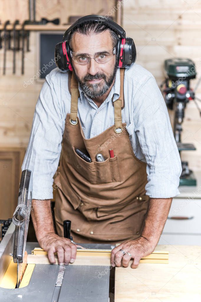 portrait of carpenter at table saw in workshop