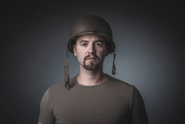 Portrait of a man in a t-shirt wearing a soldier's military helm