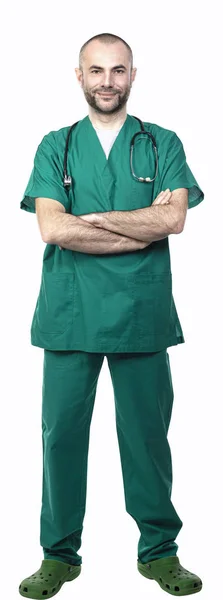 Médico de pé com uniforme verde, braços cruzados vista lateral — Fotografia de Stock