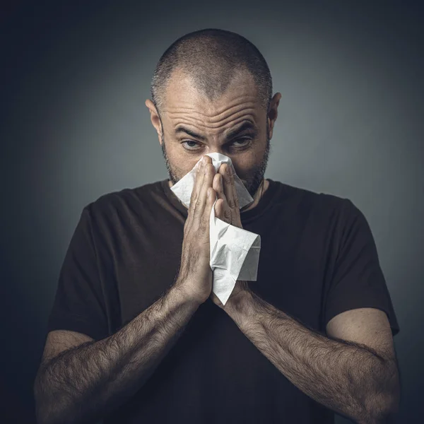 Portrait of a man blowing his nose with a tissue. look at the ca — Stock Photo, Image