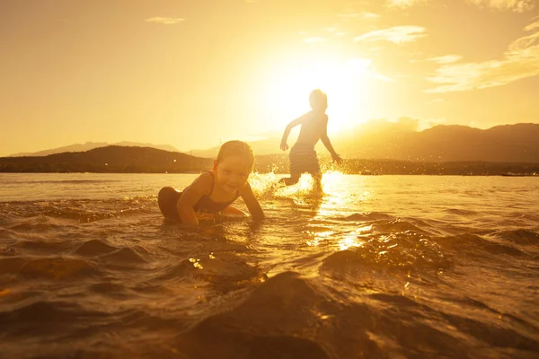 Niños alegres juegan en el mar al atardecer — Foto de Stock