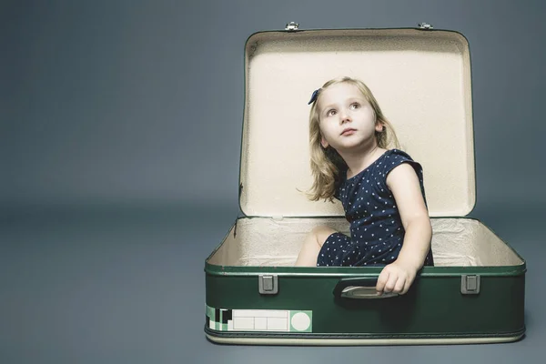 Blond meisje zitten in een vintage koffer. — Stockfoto