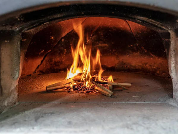 lighting the fire of a wood-fired pizza oven.